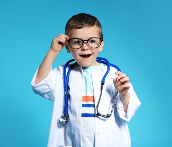 Cute child in doctor coat with stethoscope on color background